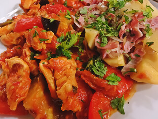 Carne de pollo con verduras en un restaurante italiano. Primer plano de un delicioso plato de comida italiana de pollo acompañado por patatas, pimientos, tomates, cebolla y calabacín.