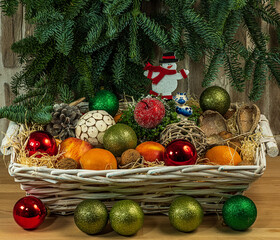 
Toys for the tree, fruits in a wicker basket. Branches from the tree hang from above. A gift for the New Year.