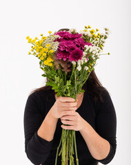 Caucasian woman covering her face with bouquet of flowers on white