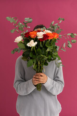 Caucasian woman covering her face with bouquet of roses on pink