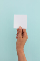 Hand of caucasian woman holding white paper over pale blue background