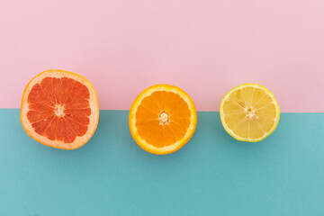Grapefruit, orange and lemon halves on pink and blue background