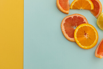 Slices of grapefruit, orange and lemon on blue and yellow background