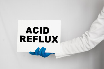 The doctor's blue - gloved hands show the word ACID REFLUX - . a gloved hand on a white background. Medical concept. the medicine