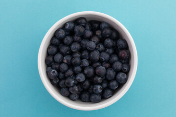 High angle view of bowl of blueberries on blue background