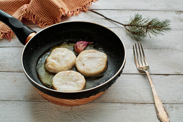 Fried hake slices and garlic in a frying pan