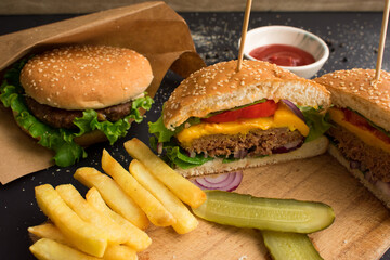 Burger and french fries on black background and wooden board