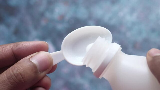 pouring liquid medicine onto a spoon top view 