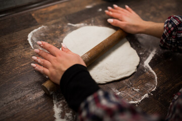 female hands roll out pizza dough