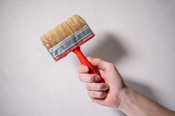 Male hand holding a brush for applying glue to the wall