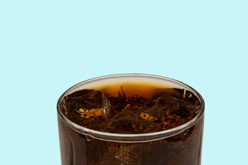 Close up view of top of full glass of soda with ice cubes isolated on blue background. Unhealthy drinks concept. Health concept. Beverage concept.