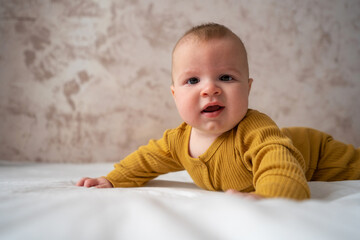 Naklejka premium Five months baby boy. Adorable baby boy in sunny bedroom. Newborn child relaxing in bed. Nursery for children