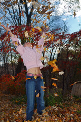 Young girl throwing Autumn leaves in the air