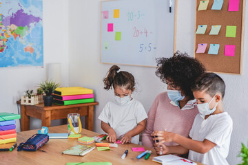 Teacher draws with preschool children while wearing protective face mask for coronavirus - School and prevention
