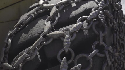 Close up on huge tractor wheel equipped with traction chain.