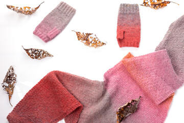 Woolen knitted shawl and gray and pink woolen mitts on a white background.