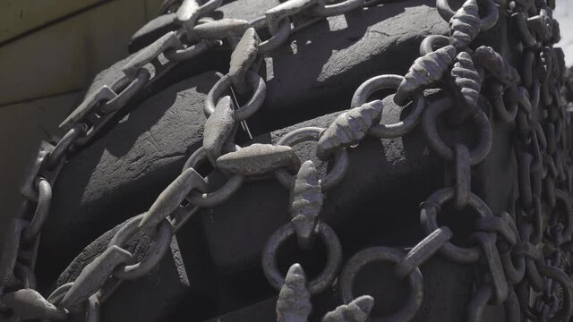Close up on huge tractor wheel equipped with traction chain.