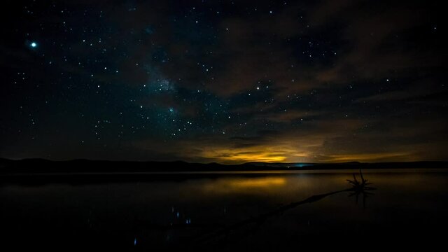 Timelapse or hyperlapse of the stars and the milky way over the lake with reflections