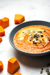 Homemade Pumpkin cream soup with chees and seeds on the white background