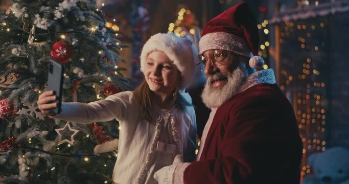 Happy girl taking selfie with Santa Claus