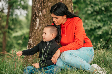 Naklejka na ściany i meble Beautiful woman spends time with a child in nature.