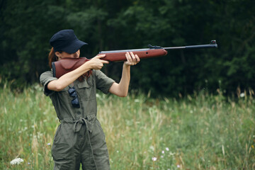 Woman on nature with a gun in his hands, aiming a green jumpsuit weapons 