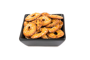 Salty round pretzel pieces in a bowl isolated over white