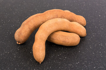 Three pieces dried brown tamarind pods isolated over black