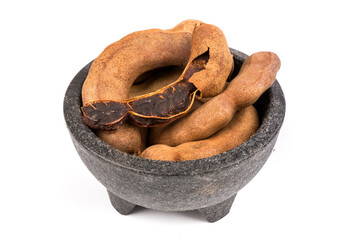 Dried brown tamarind pods in a black bowl isolated over white open pod of top