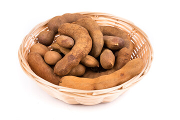 Dried brown tamarind pods in a glass bowl isolated over white