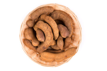 Dried brown tamarind pods in a glass bowl isolated over white top down view