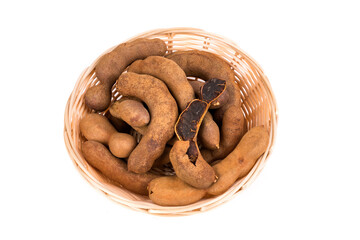 Dried brown tamarind pods in a bowl isolated over white