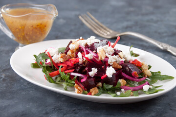 on a gray background  a plate with beet salad and gravy boat