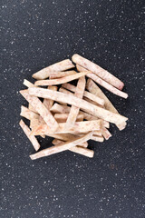 Pile of dehydrated taro snack sticks isolated over black top down view