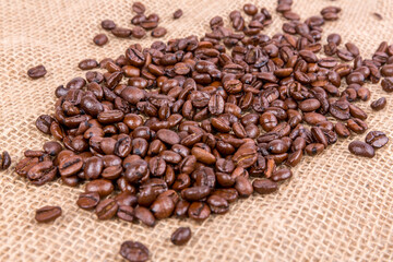 Pounds of roasted brown coffee beans over a burlap textured cloth