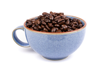 Blue ceramic cup filled with brown roasted coffee beans isolated over white