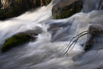 Stream of water between stones with a bent branch