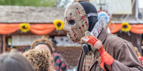 Fototapeta na wymiar Masked man with an ax looking like a psychopath walks the streets