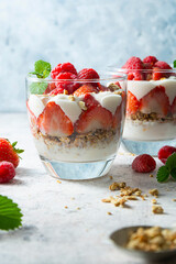Two glasse with layered yogurt, granolla and fruits, strawberry ans raspberry. Healthy breakfast.