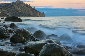 Rocky shore of the Black Sea and Mount Karadag in the evening light in Crimea