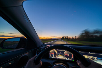Movement of the car at night at high speed view from the interior with driver hands on wheel. Concept speed of life.