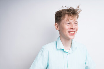 Handsome Caucasian boy with a messy hair smiling on a white background