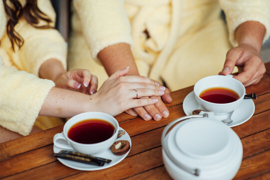 A loving couple sits in dressing gowns and drinks tea on a wooden table