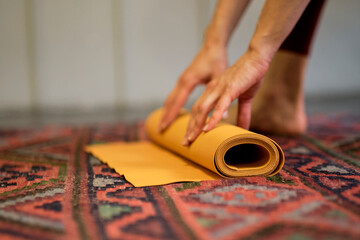 Fototapeta na wymiar Woman rolling her mat after a yoga class