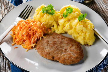 Minced meat cutlet served with mashed potatoes and carrot salad.
