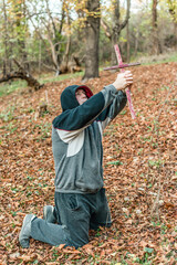 Fototapeta premium The man kneels in prayer and holds the cross up.