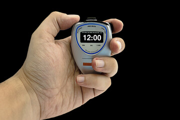 Closeup of a white man's hand holding an electronic timer on an isolated black background