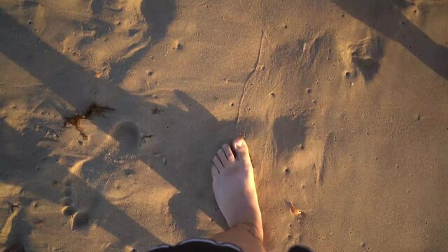 Pies andando por la arena de la playa