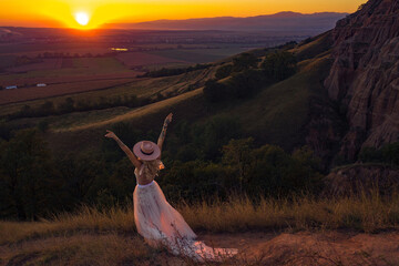 Beautiful boho chic woman on the hill enjoying an amazing sunset with gratitude