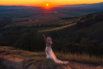 Beautiful boho chic woman on the hill enjoying an amazing sunset with gratitude